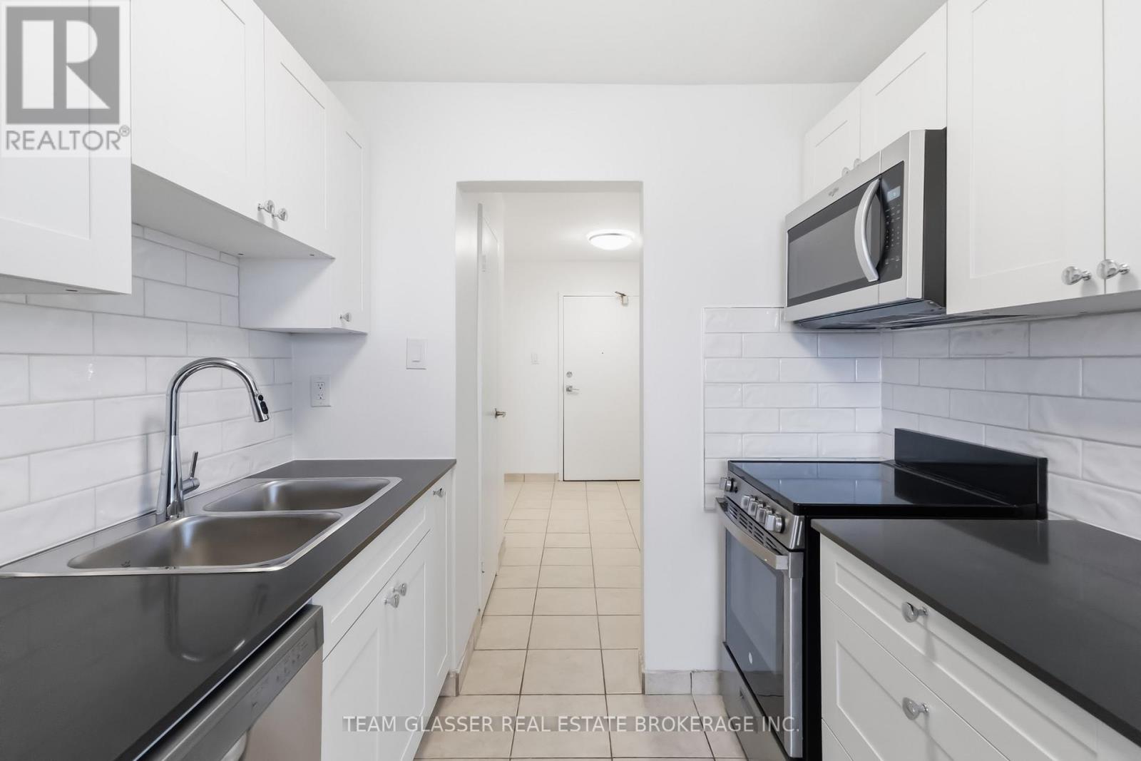 A kitchen with white cabinets and black countertops.