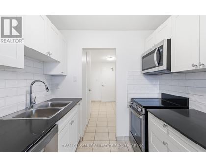 A kitchen with white cabinets and black countertops.