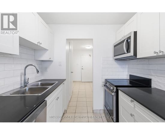 A kitchen with white cabinets and black countertops.