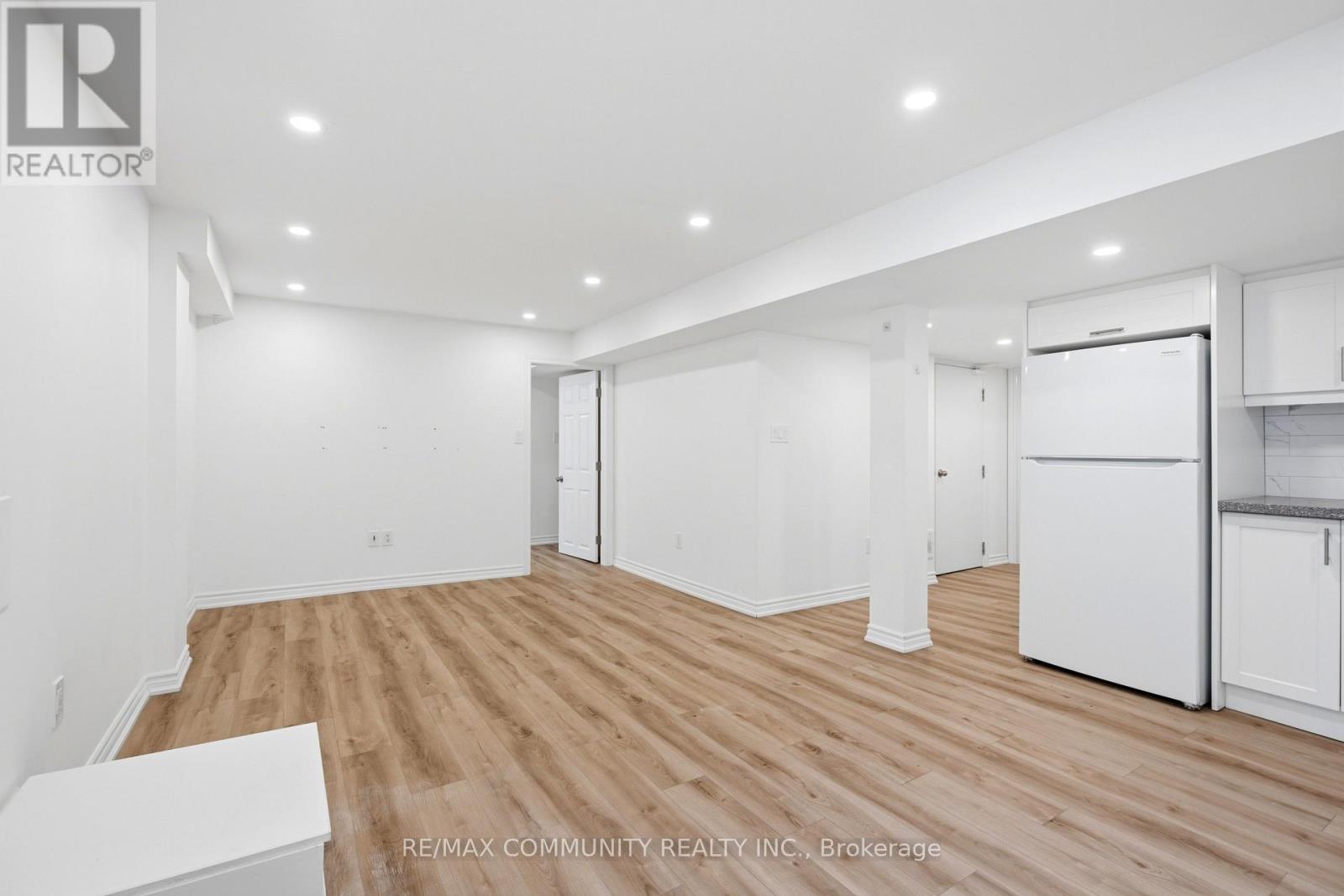 A spacious room with wooden flooring and white walls.