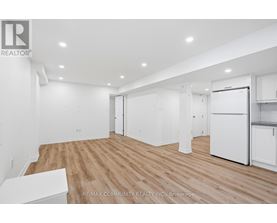 A spacious room with wooden flooring and white walls.