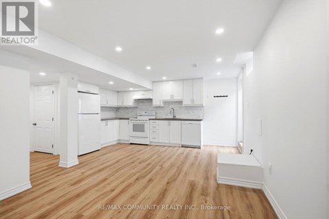 A spacious kitchen with white cabinets and a wooden floor.