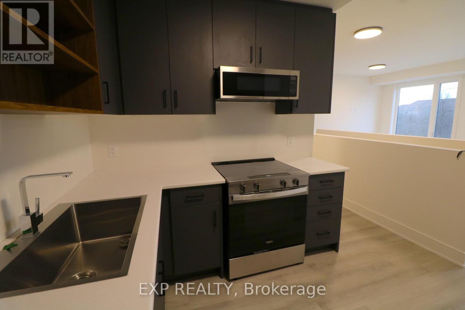 A modern kitchen with black cabinets and stainless steel appliances.