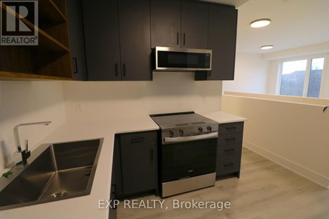 A modern kitchen with black cabinets and stainless steel appliances.