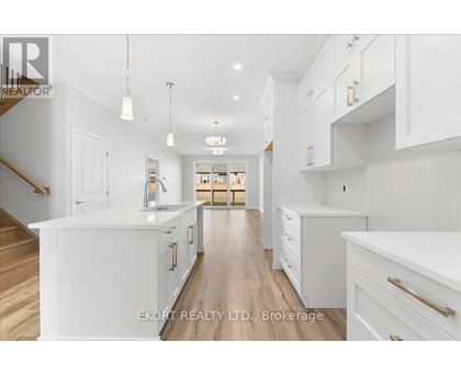 A spacious kitchen with white cabinets and a wooden floor.