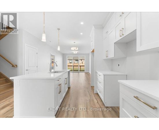 A spacious kitchen with white cabinets and a wooden floor.