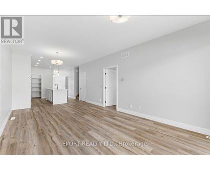A spacious room with wooden flooring and white walls, ready for furnishing.
