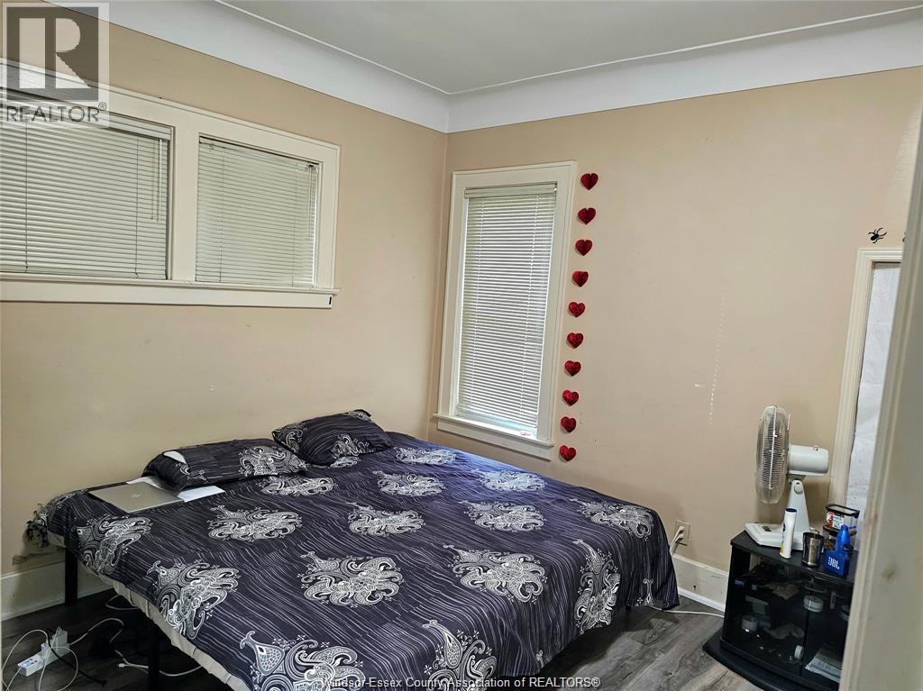 A bedroom with a bed, nightstand, and window with blinds.