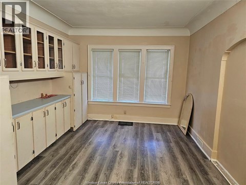A kitchen with white cabinets and a grey floor.