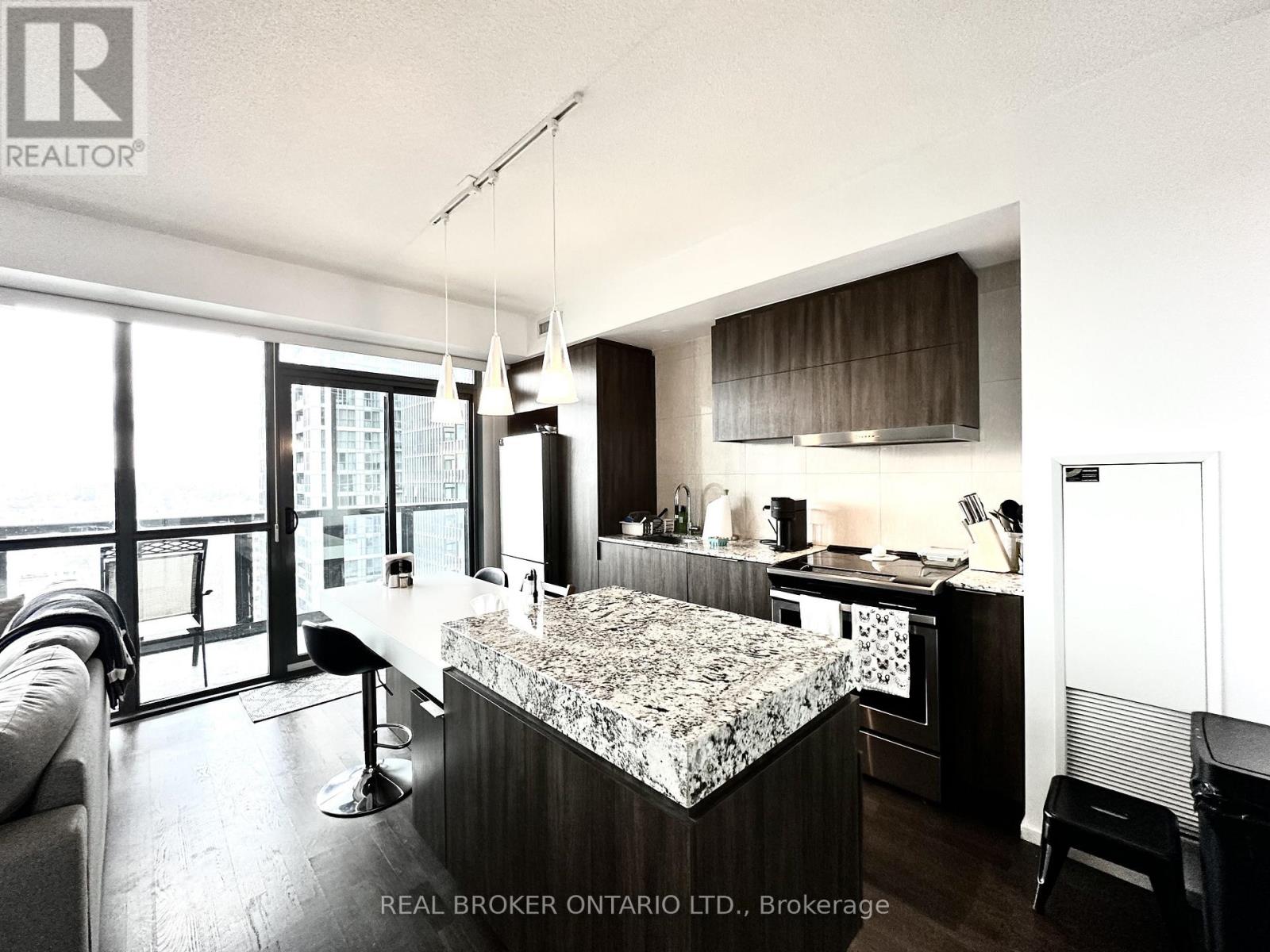 A modern kitchen with a marble island and a dining area with a table and chairs.
