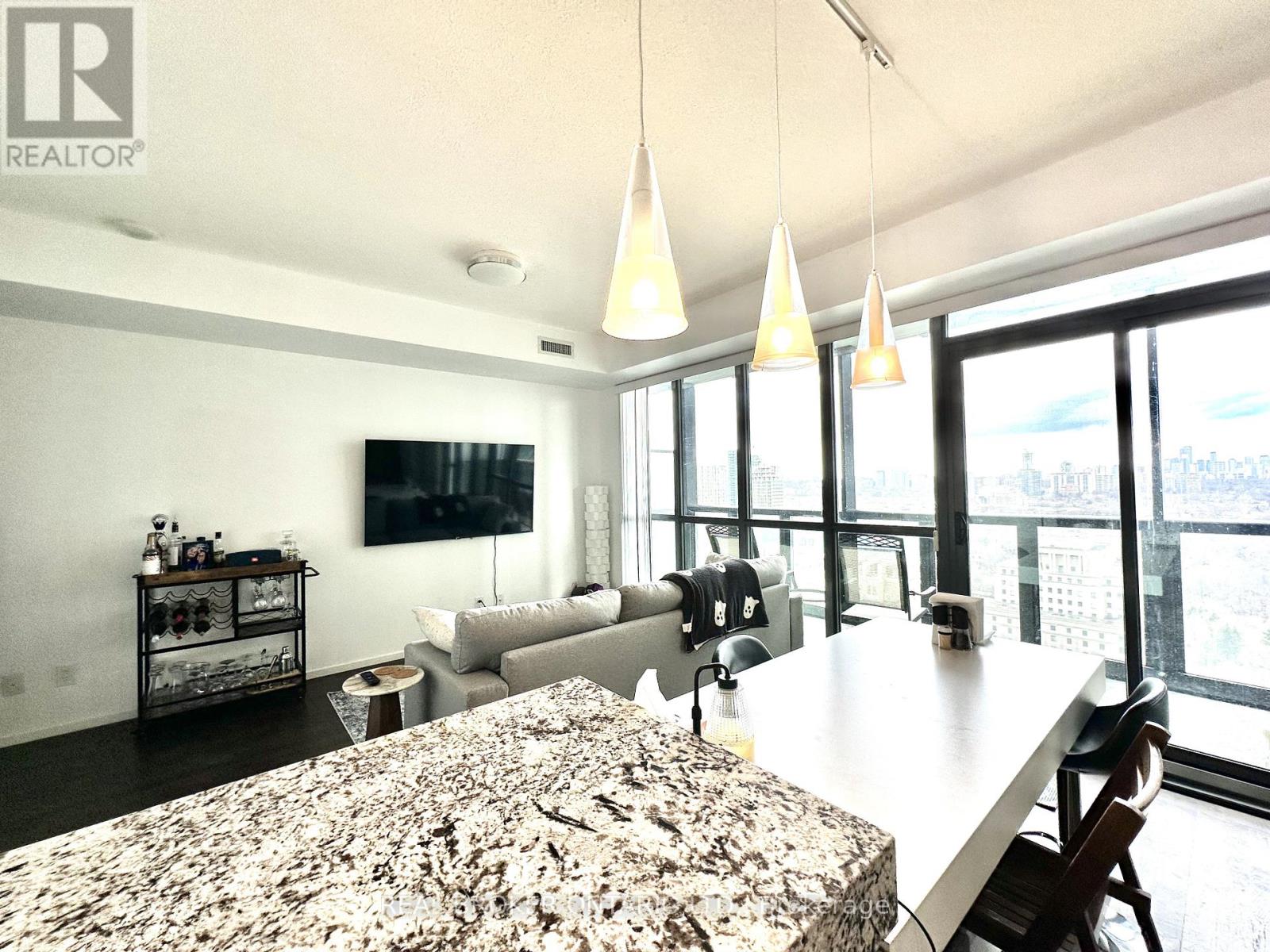 A well-lit dining room with a marble table and a television on the wall.