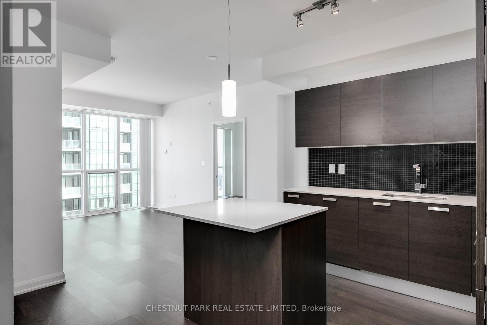 A modern kitchen with dark wood cabinets and a white island.