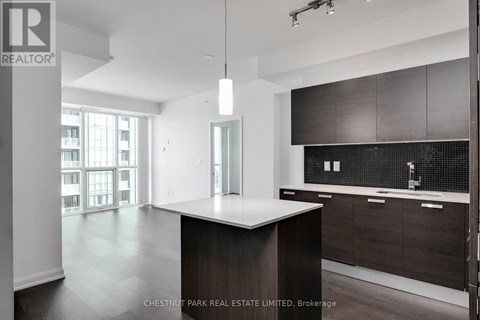 A modern kitchen with dark wood cabinets and a white island.