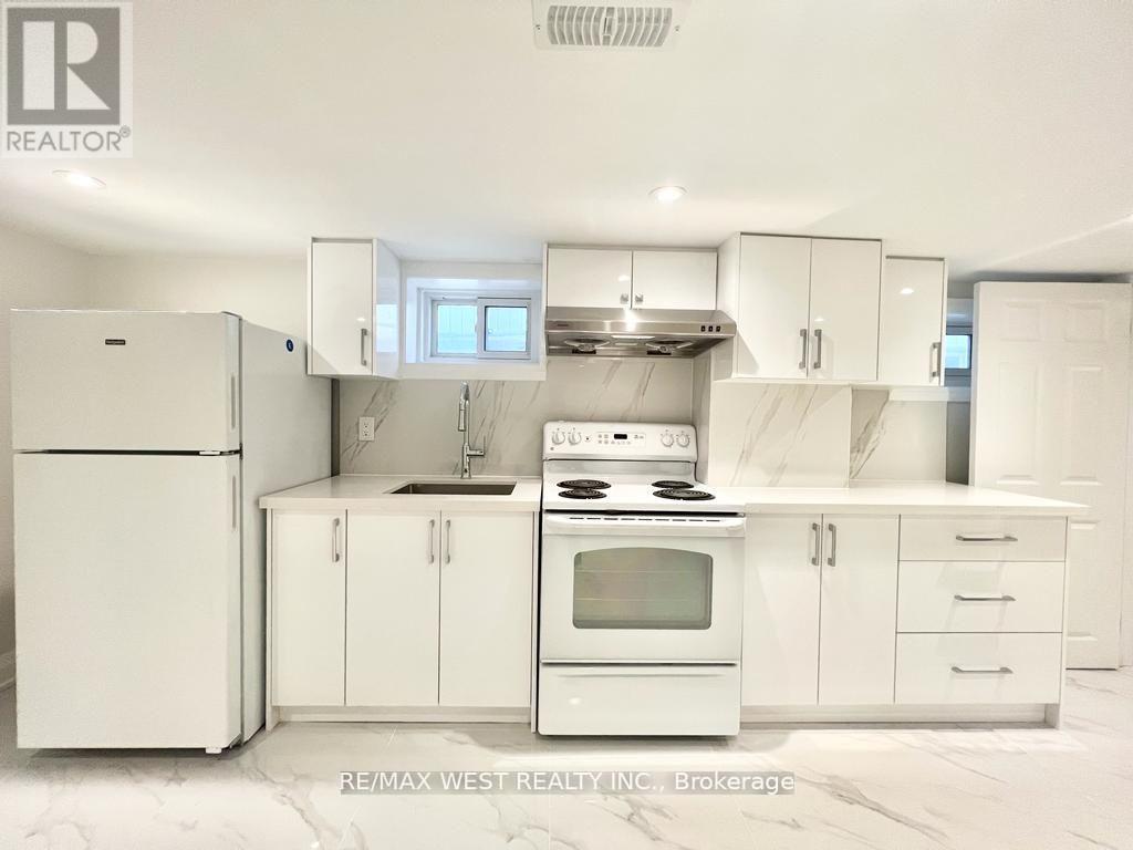 A white kitchen with a refrigerator, stove, and cabinets.