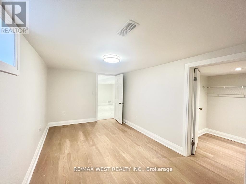 A spacious room with wooden flooring and white walls, with a door on the right side.