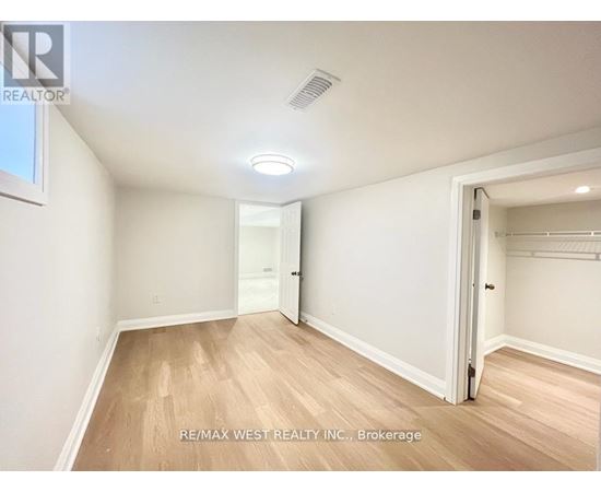 A spacious room with wooden flooring and white walls, with a door on the right side.