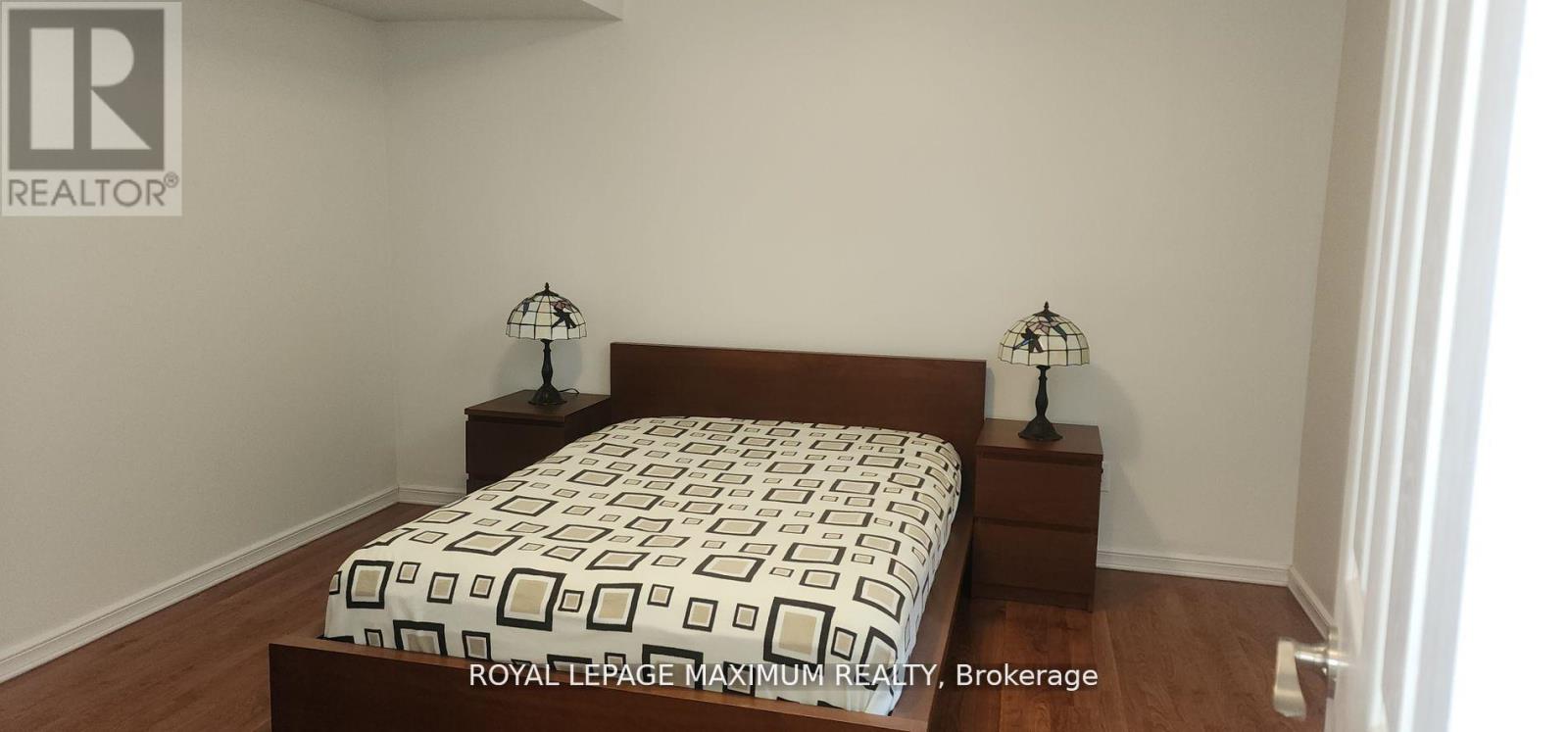 A bedroom with a bed and two nightstands with lamps.