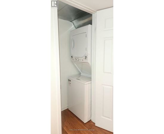 A white refrigerator is installed in a narrow space under a door.