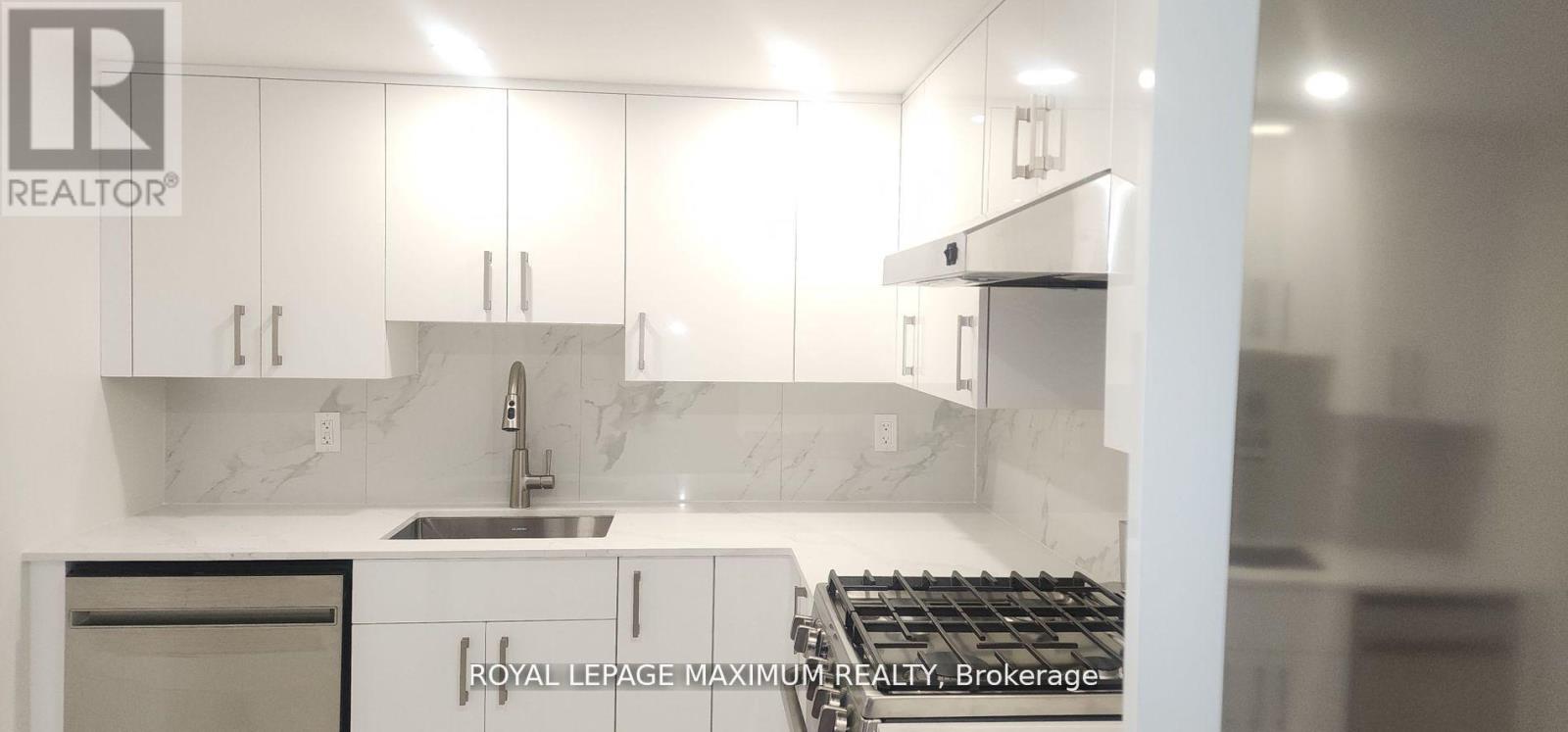 A modern kitchen with white cabinets and a marble backsplash.