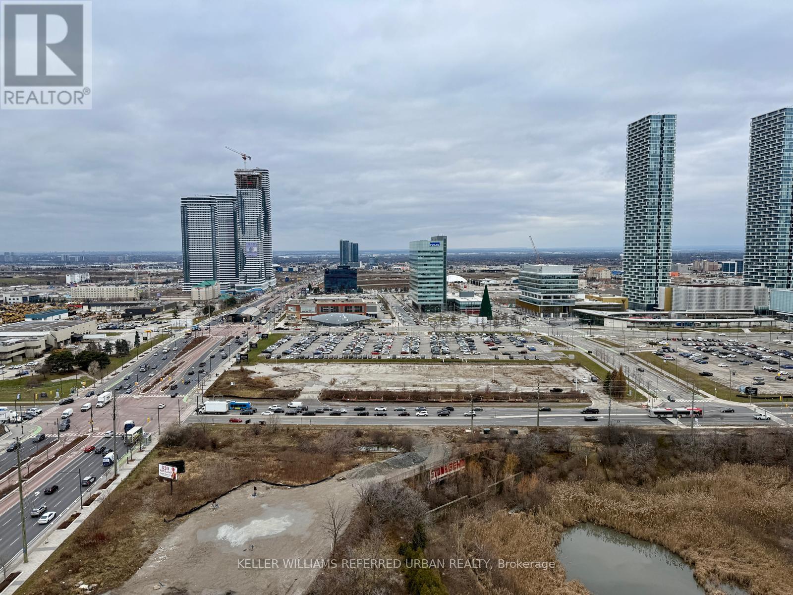 A cityscape with a mix of modern and older buildings, a busy highway, and a construction site in the foreground.