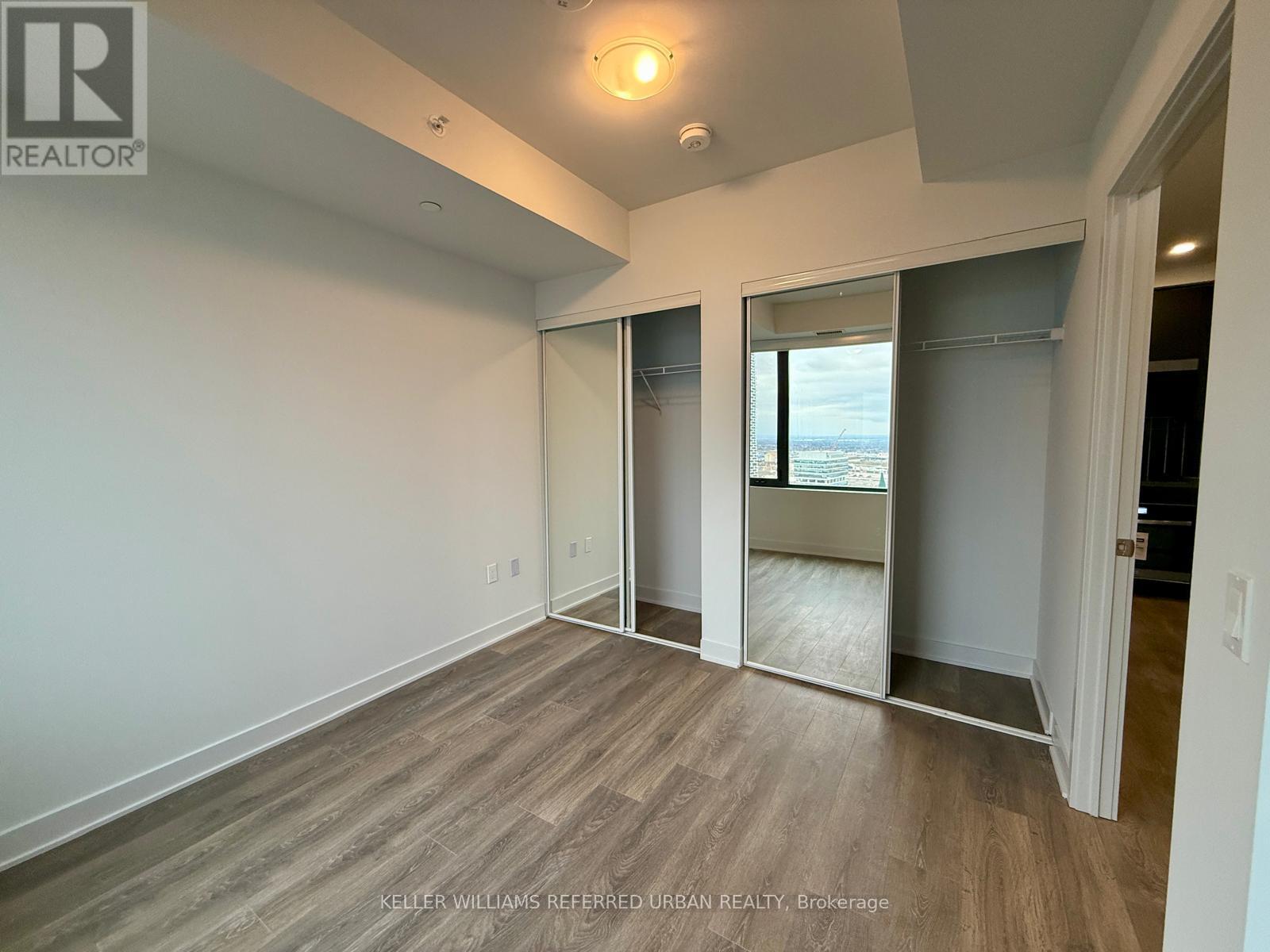 A spacious room with a sliding glass door leading to a balcony.