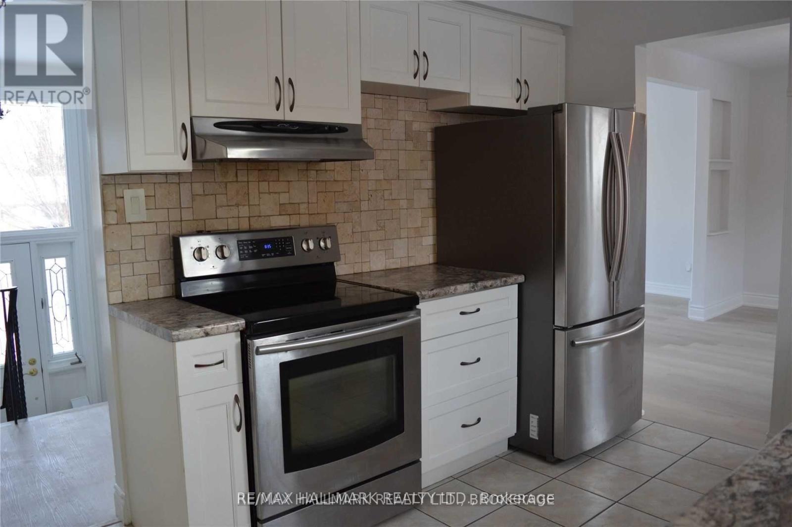 A kitchen with white cabinets and a black refrigerator.