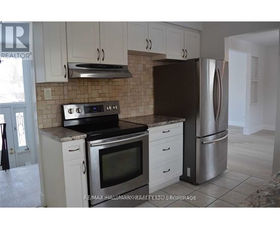 A kitchen with white cabinets and a black refrigerator.