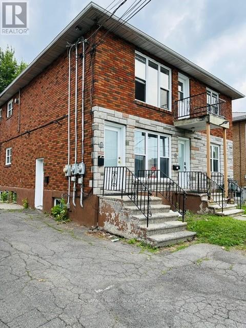 A brick house with a white door and a black metal railing on the steps.