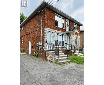 A brick house with a white door and a black metal railing on the steps.