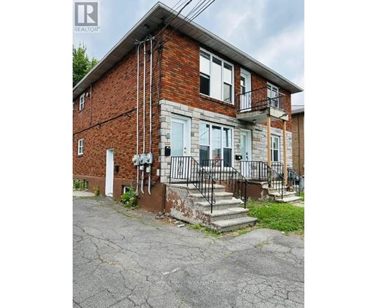 A brick house with a white door and a black metal railing on the steps.