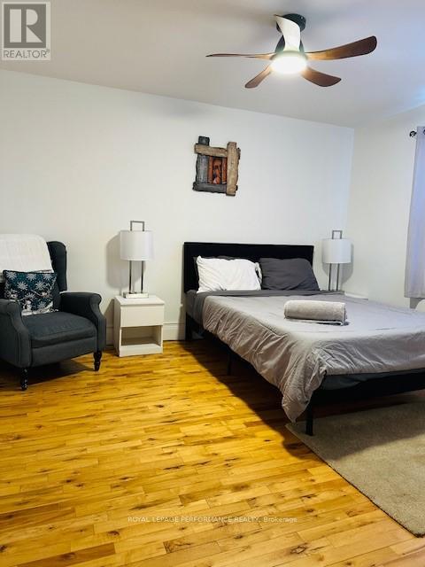 A bedroom with a bed, chair, and ceiling fan.