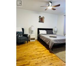 A bedroom with a bed, chair, and ceiling fan.