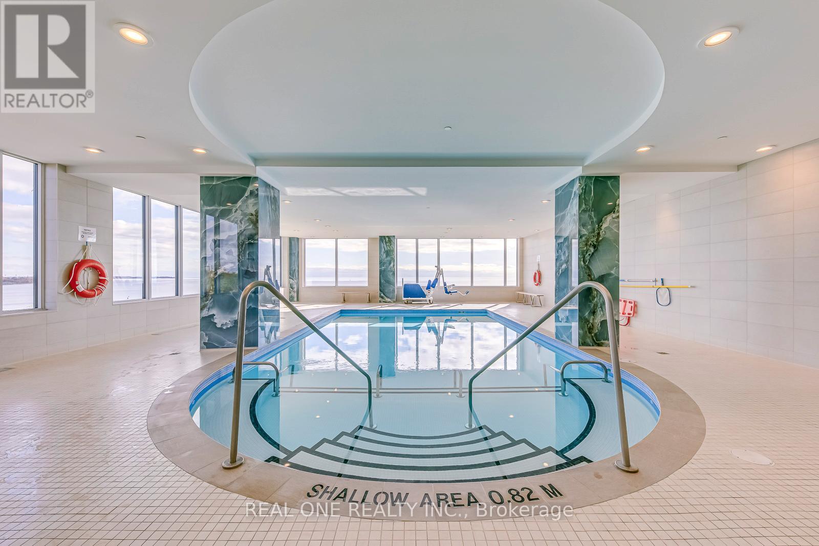 A large indoor swimming pool with a glass bottom and a glass wall on one side.