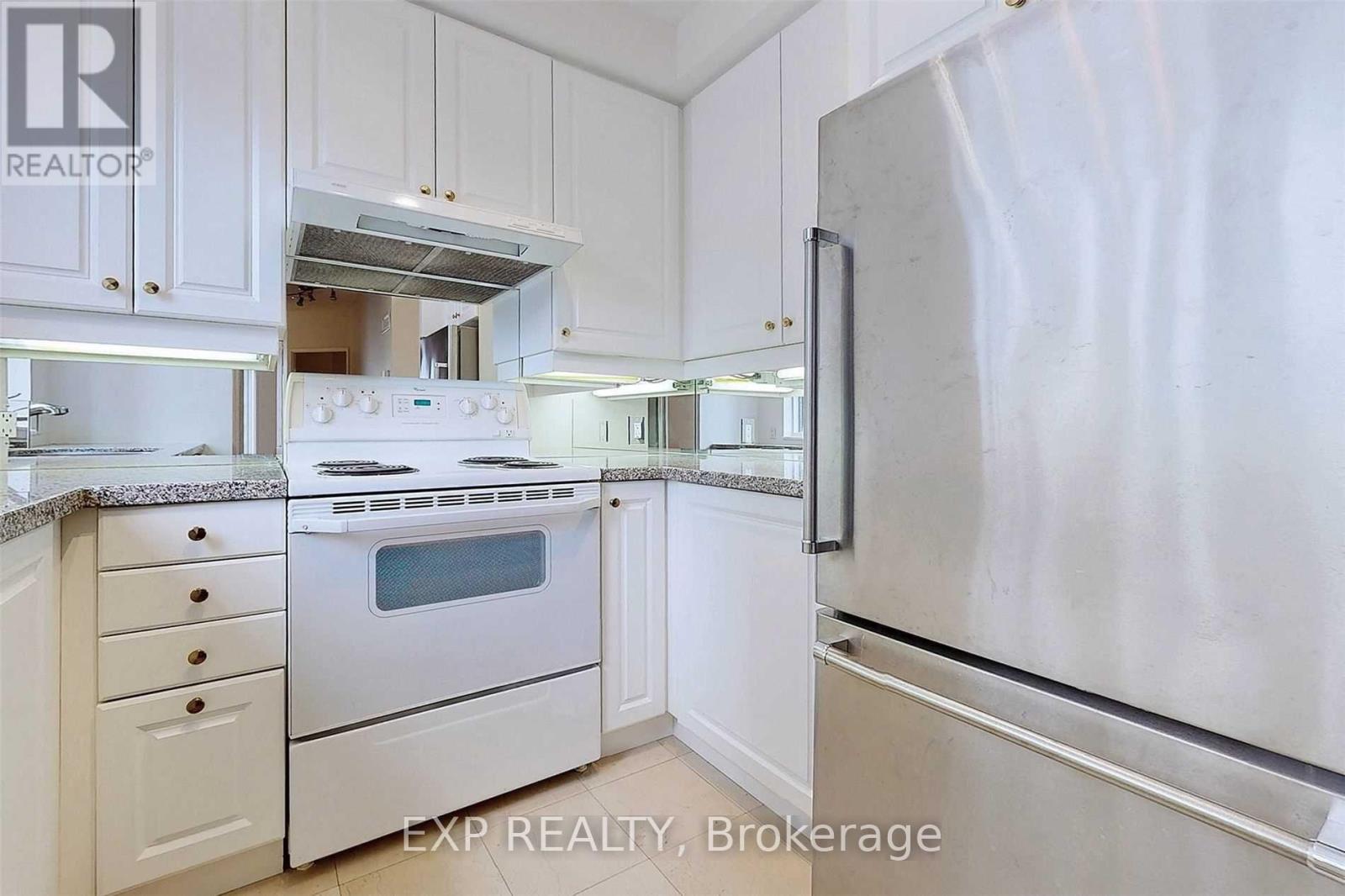 A white kitchen with a refrigerator on the right.