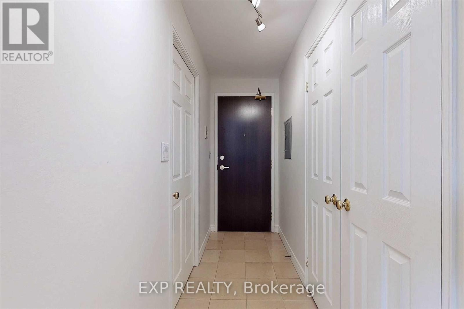 A hallway with white walls and a black door.