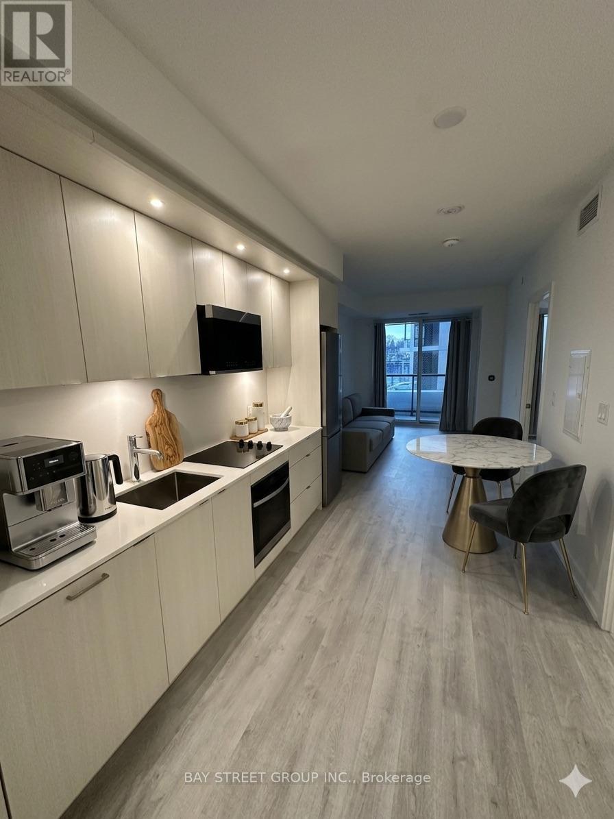 A modern kitchen with white cabinets and a wooden floor.