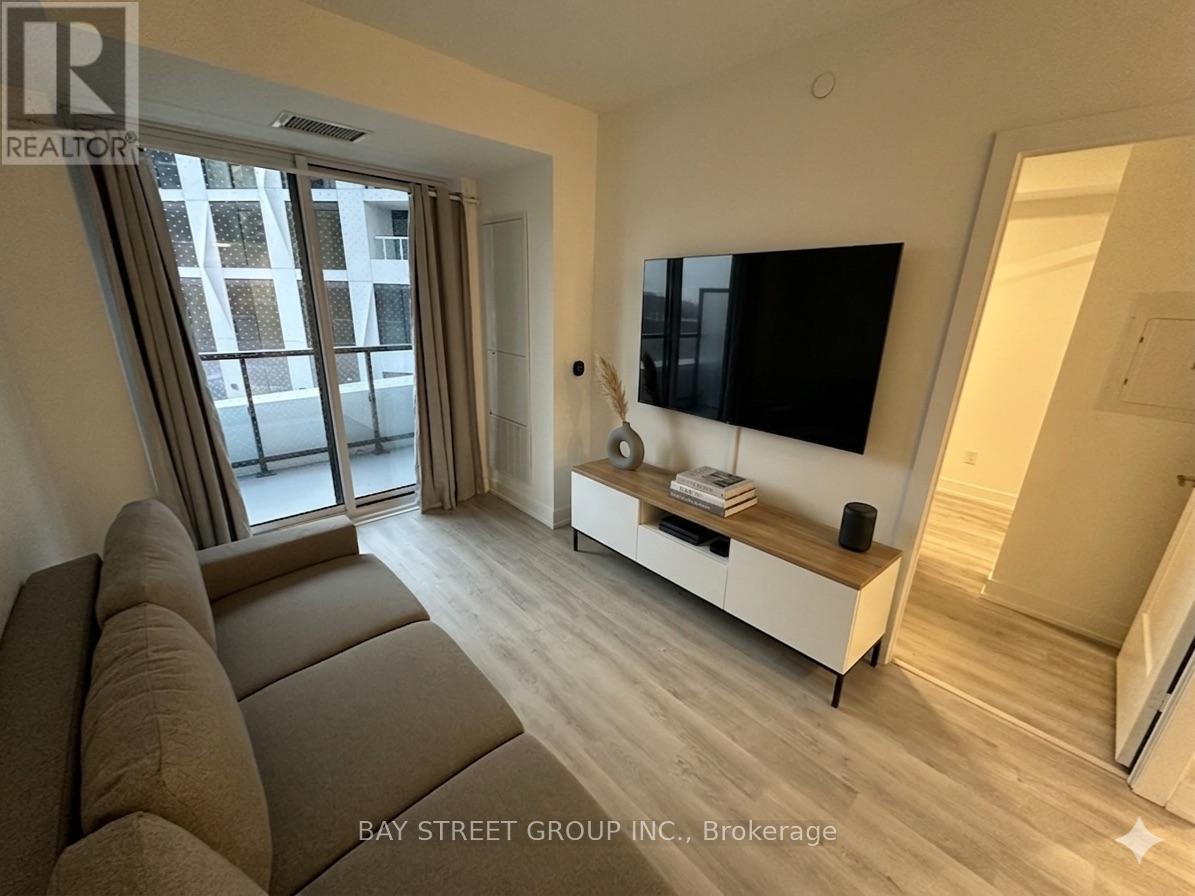A living room with a brown sofa and a flat screen TV mounted on the wall.