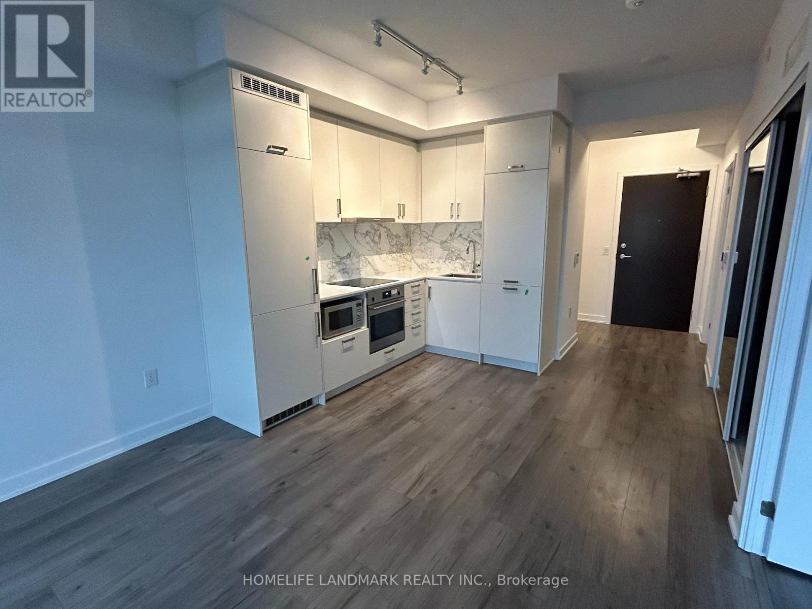 A kitchen with white cabinets and a wooden floor.