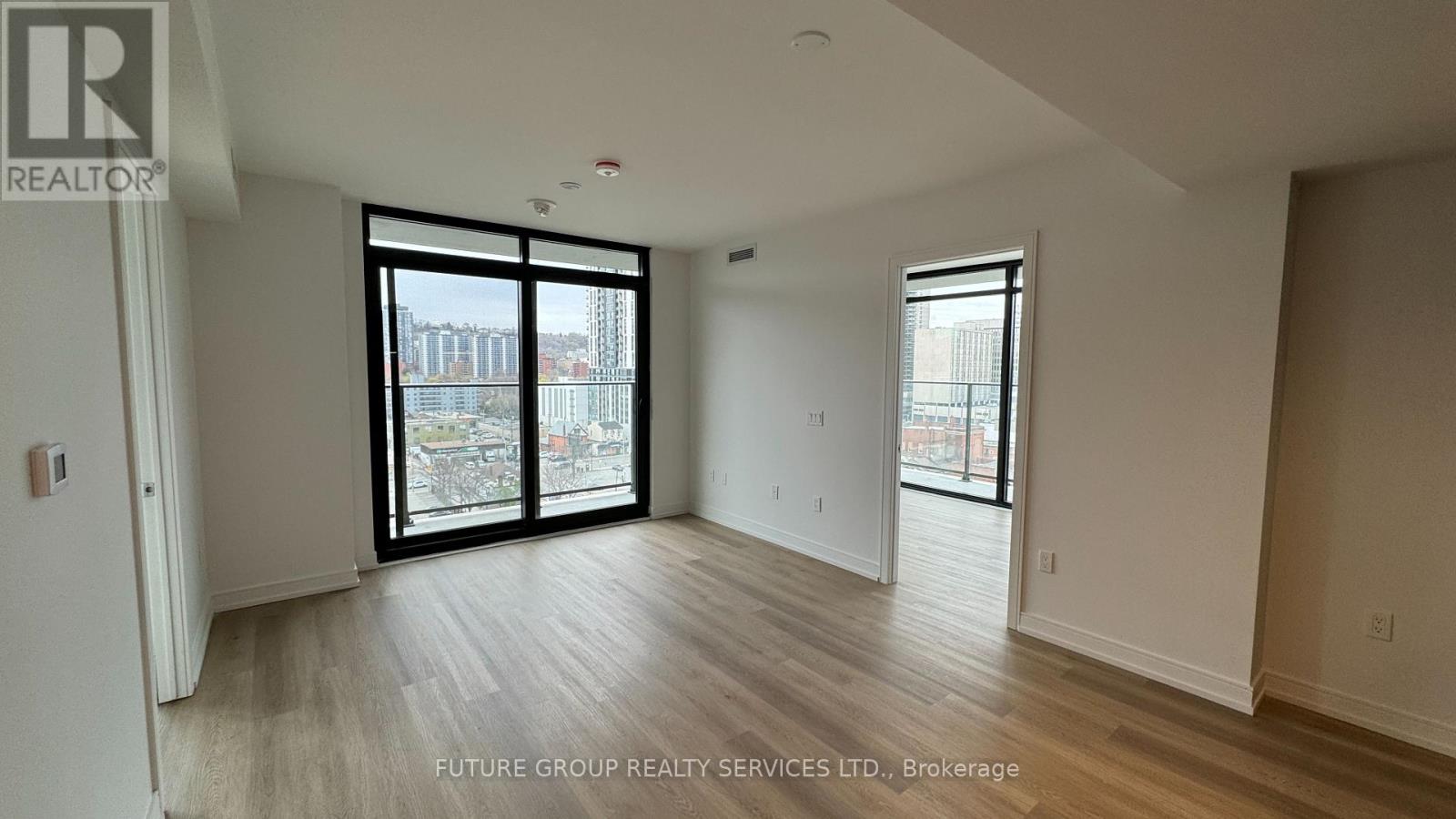 A spacious room with a sliding glass door leading to a balcony.