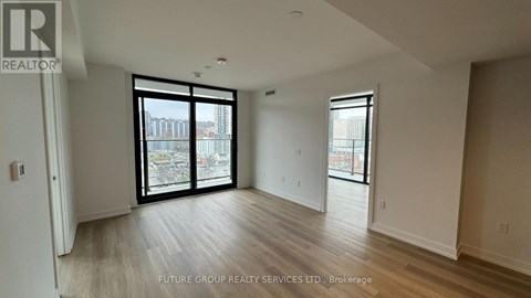 A spacious room with a sliding glass door leading to a balcony.