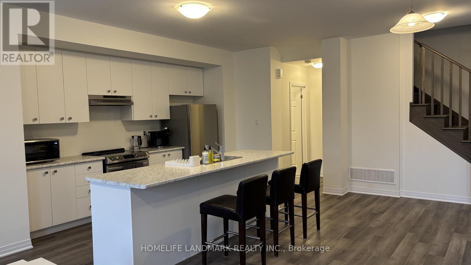A kitchen with white cabinets and a white island with four black chairs.