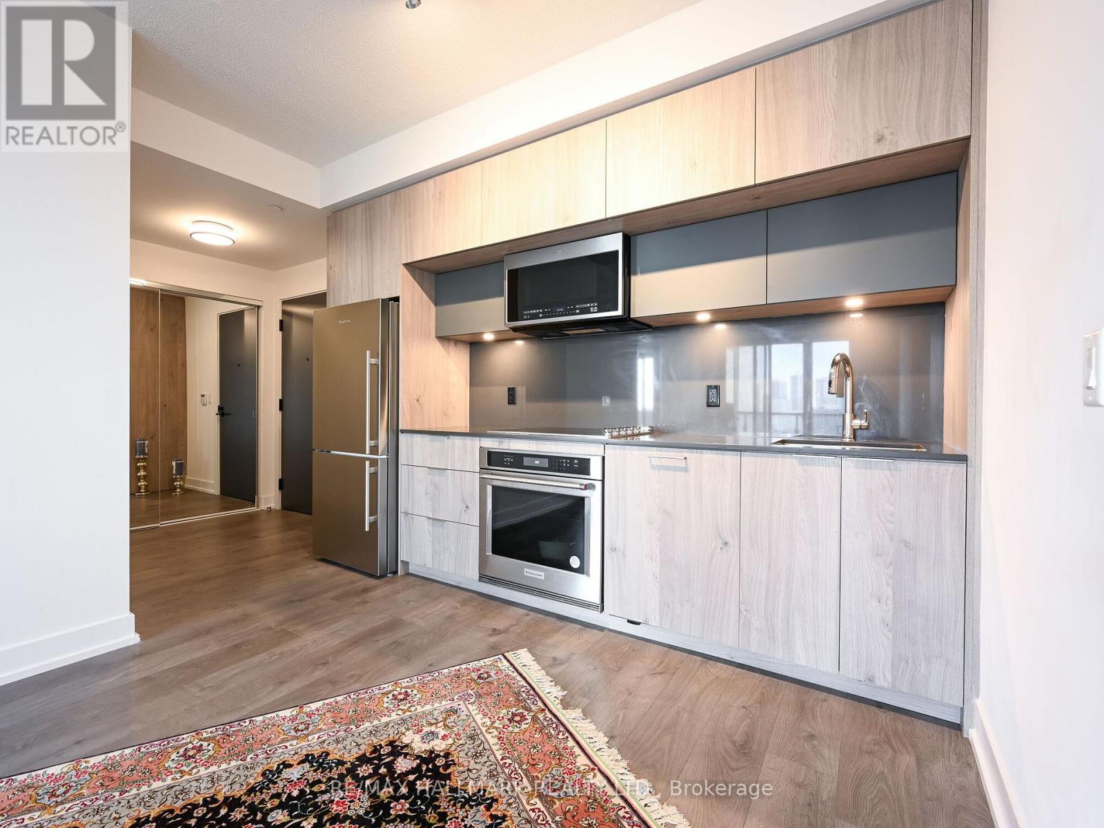 A modern kitchen with wooden cabinets and a rug on the floor.