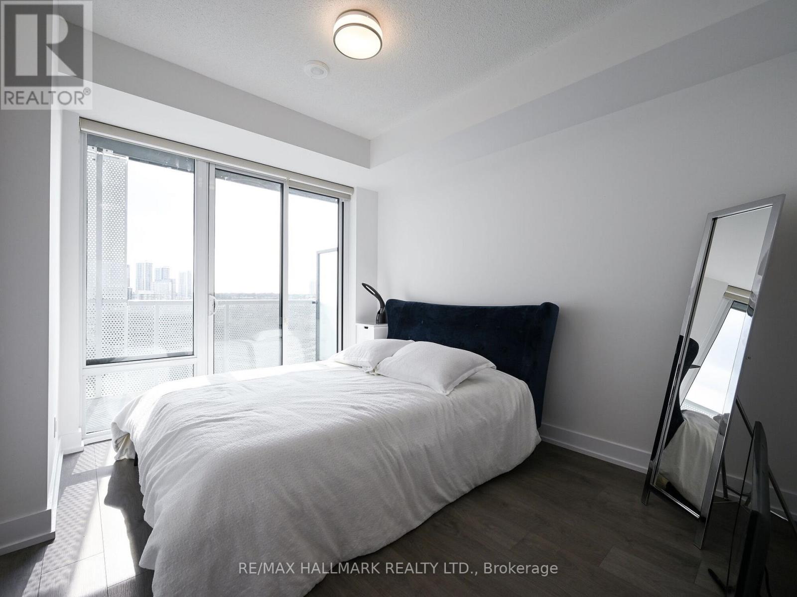 A bedroom with a large bed and a view of the city through the window.