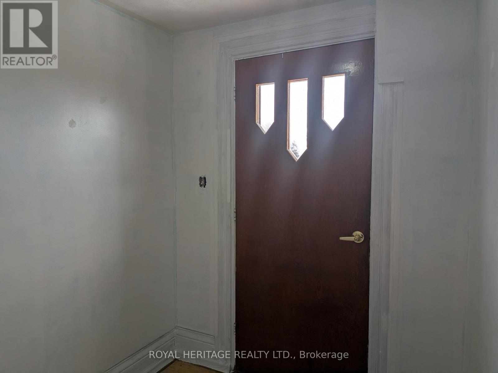 A dark brown door with a gold handle in a white room.