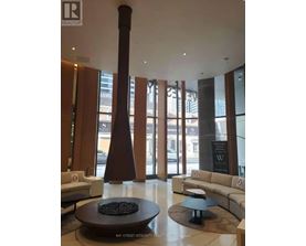A large room with a couch, a table and a tall column.