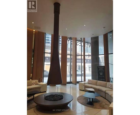A large room with a couch, a table and a tall column.