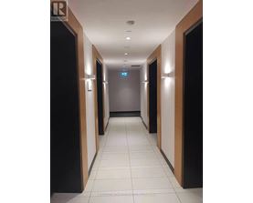 A long hallway with doors on both sides and a blue sign in the middle.
