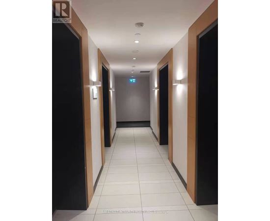 A long hallway with doors on both sides and a blue sign in the middle.
