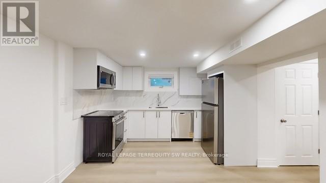 A kitchen with white cabinets and a black fridge.