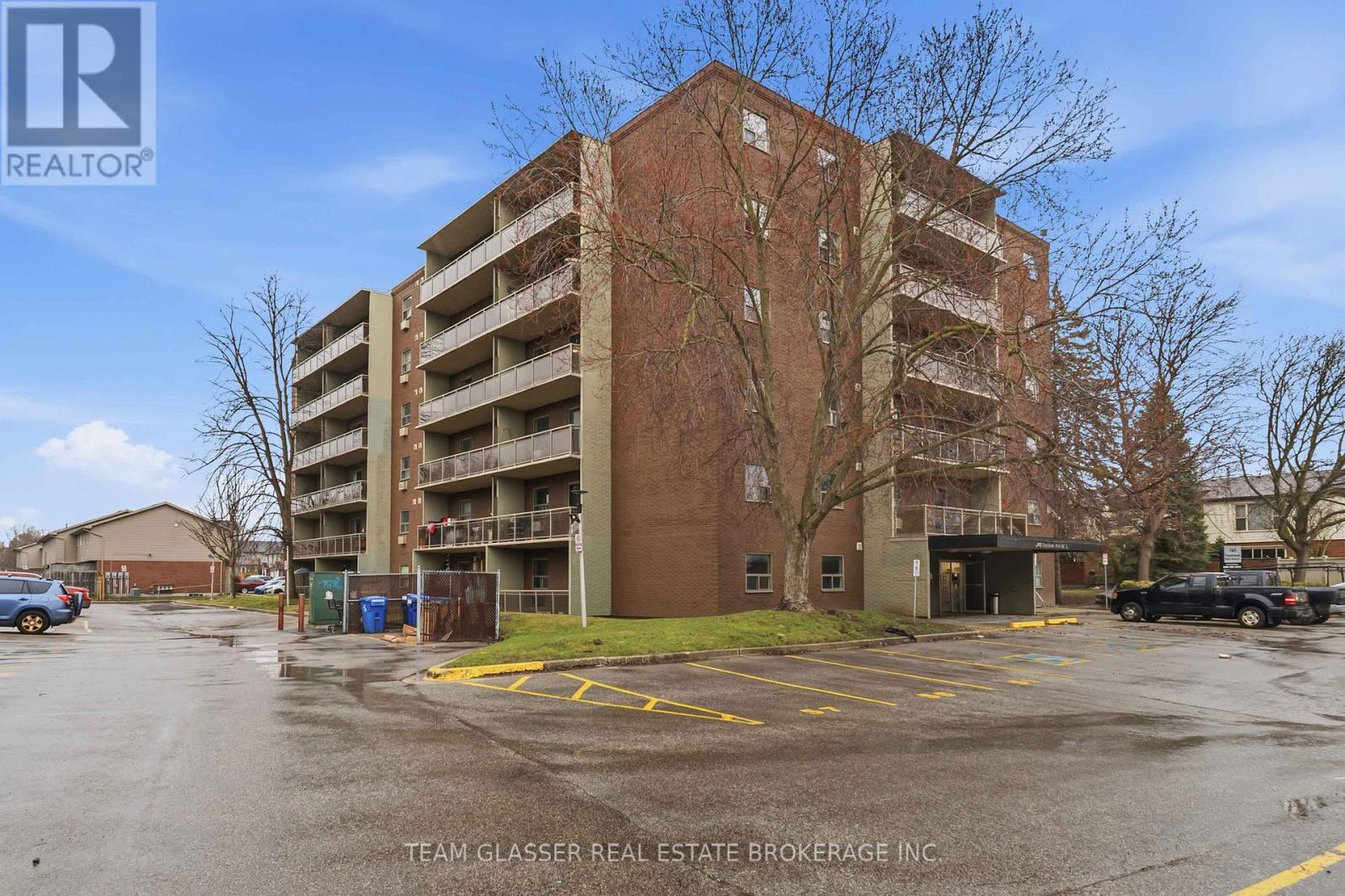 A large brick apartment building with a parking lot in front.